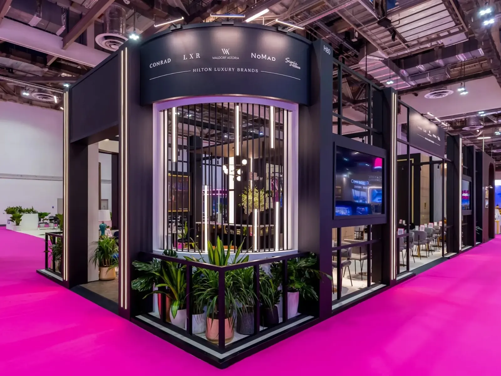 Fuarda Hilton Luxury Brands için siyah, ışıklı çizgili stand ve pembe zemin